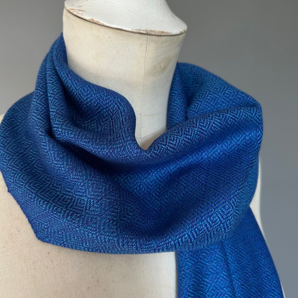 Blue textured scarf on a mannequin against a gray background