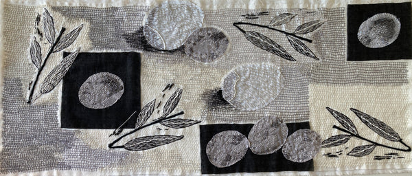 Textile art piece with black and white patterns on a plain background