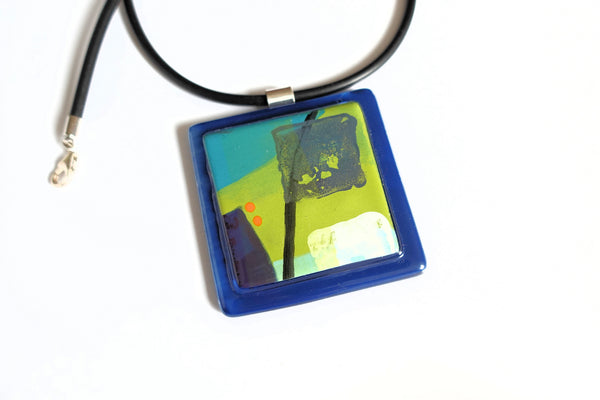 square glass pendant 5x5cm. navy base with lime green and cyan enamel design. Orange dots highlights of colour