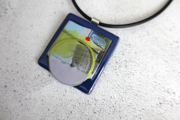 5cm square fused glass pendant. abstract design in lime green and navy with red highlights. silver bail and rubber necklace