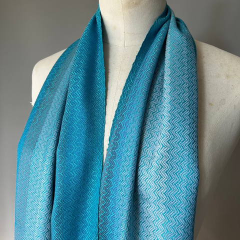 Blue patterned scarf on a mannequin against a gray background